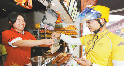 湖北省襄阳市，一位快递小哥正在商家取顾客在外卖平台上预订的餐品。 　　人民视觉